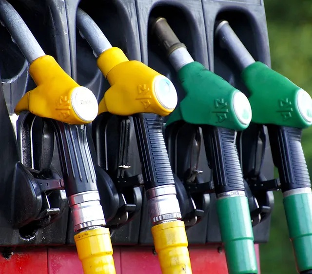 Y'all, check this out! We've got a close-up shot of the gas pump nozzles right here at our fuel station. Whether you're packin' diesel or regular, we’ve got you covered with four trusty pumps sportin’ bright yellow and green handles to signify different fuel types. Those nozzles are hangin' snug in their holders, primed and ready to fill ‘er up!