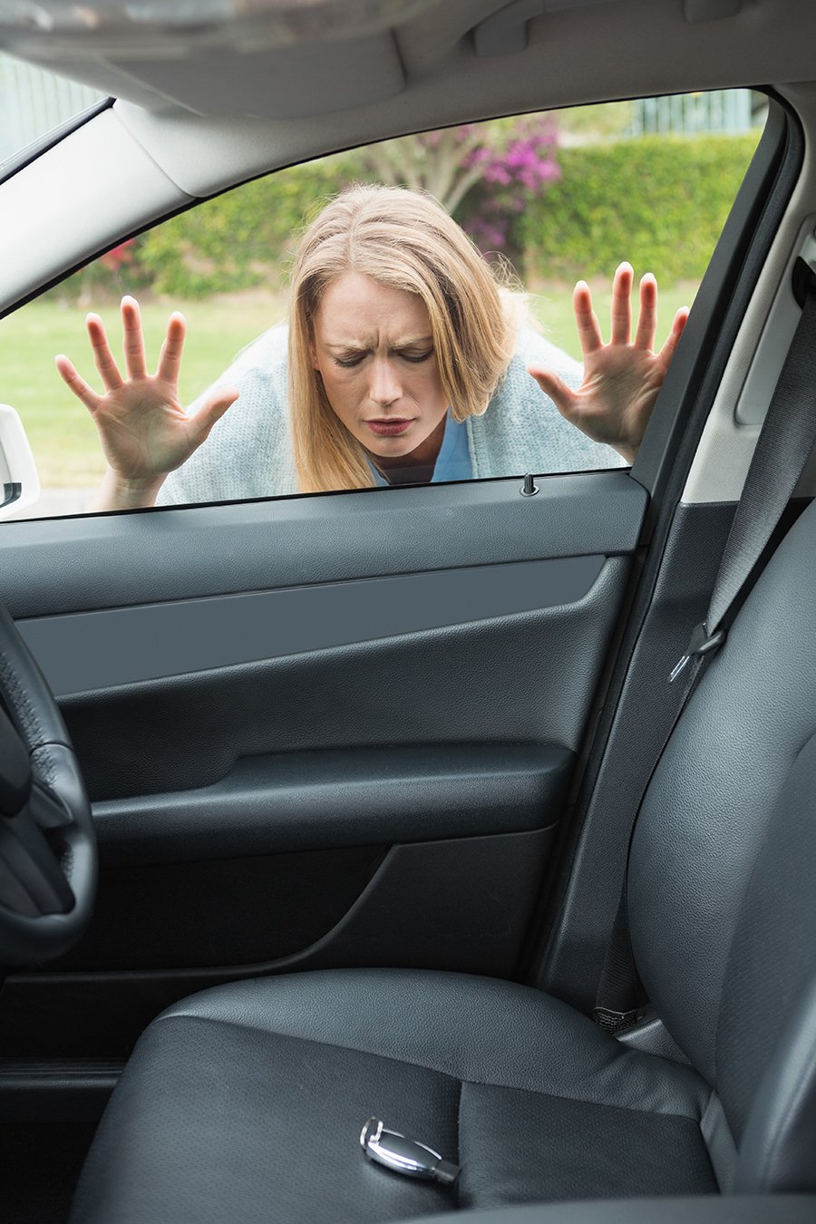 Y'all, picture this: a lady with blonde hair, donned in a cozy gray sweater, standing outside her locked car window. She looks mighty troubled as she gazes inside at the set of car keys sittin' right there on the driver's seat. Don't worry ma'am, Dallas Towing Service is on its way to save the day!