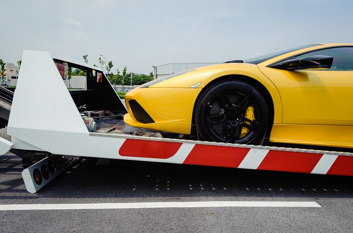 Howdy folks! At Big Tex Towing, we’re your trusty roadside heroes ready to help you get back on track. Check out this vibrant yellow sports car being expertly loaded onto the back of one of our reliable white tow trucks, decked out with striking red diagonal stripes. With the sun shining bright overhead, we've got that front wheel carefully nestled on our sturdy platform. Whether it's a sunny day or any day, Big Tex Towing is here to give you a lift – no matter what you're drivin'!